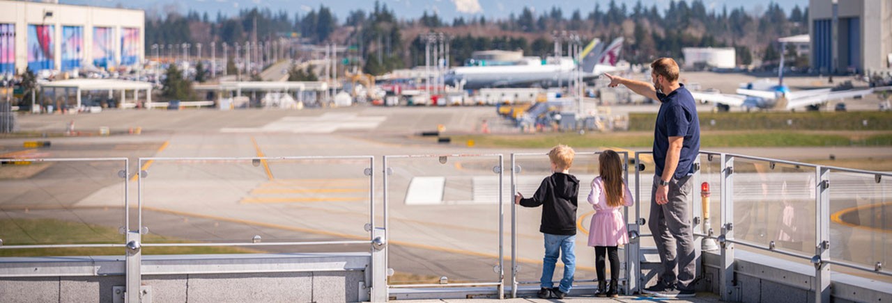 A family stands at the railing of the Sky Deck at Boeing Future of Flight, overlooking the Boeing Everett Factory.
