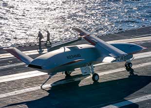 MQ-25 with folded wings on flight deck
