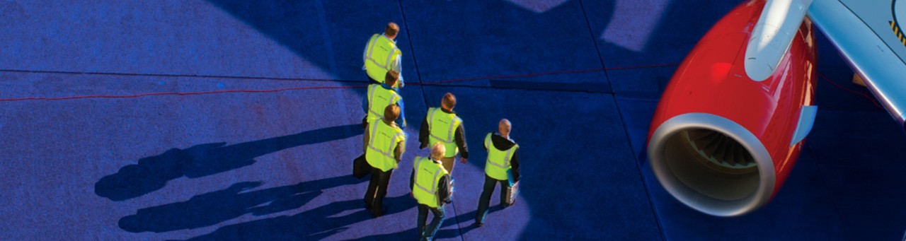 6 workers in high visiblity vests walk towards an engine.