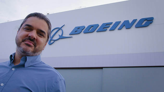 Jinnah Hosein standing in front of Boeing logo on wall
