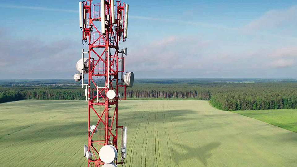 5G tower in a field with airplane shadow